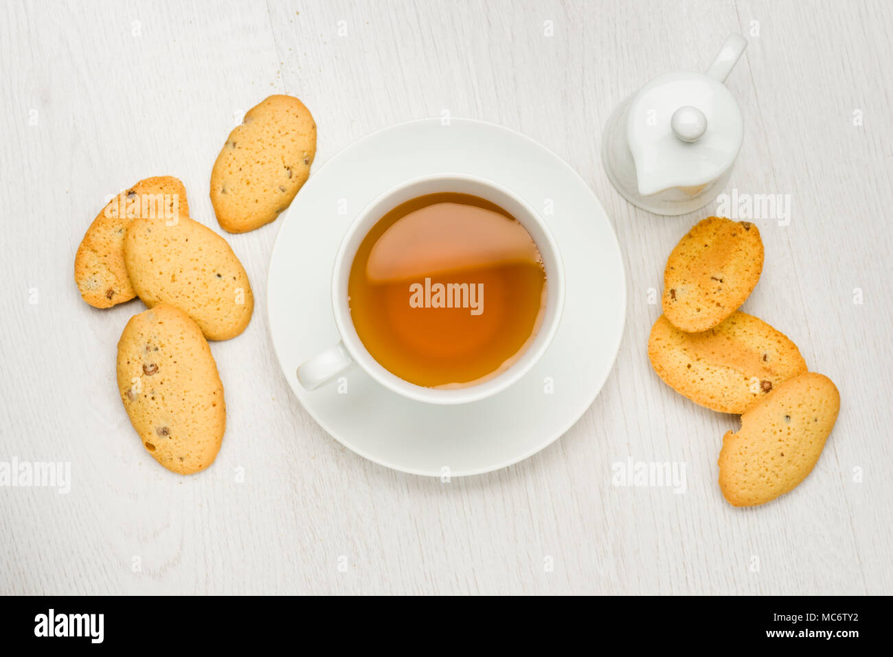 Tazza di tè sul tavolo bianco con i cookie e bricco per il latte Foto Stock