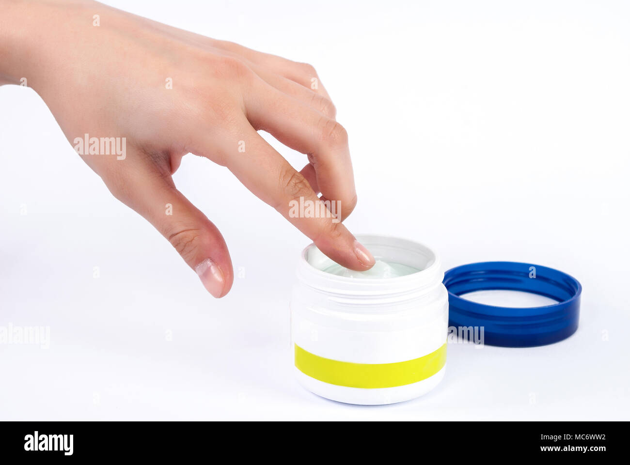 Delicato mano femmina mette il dito in una ciotola di crema per il viso Foto Stock