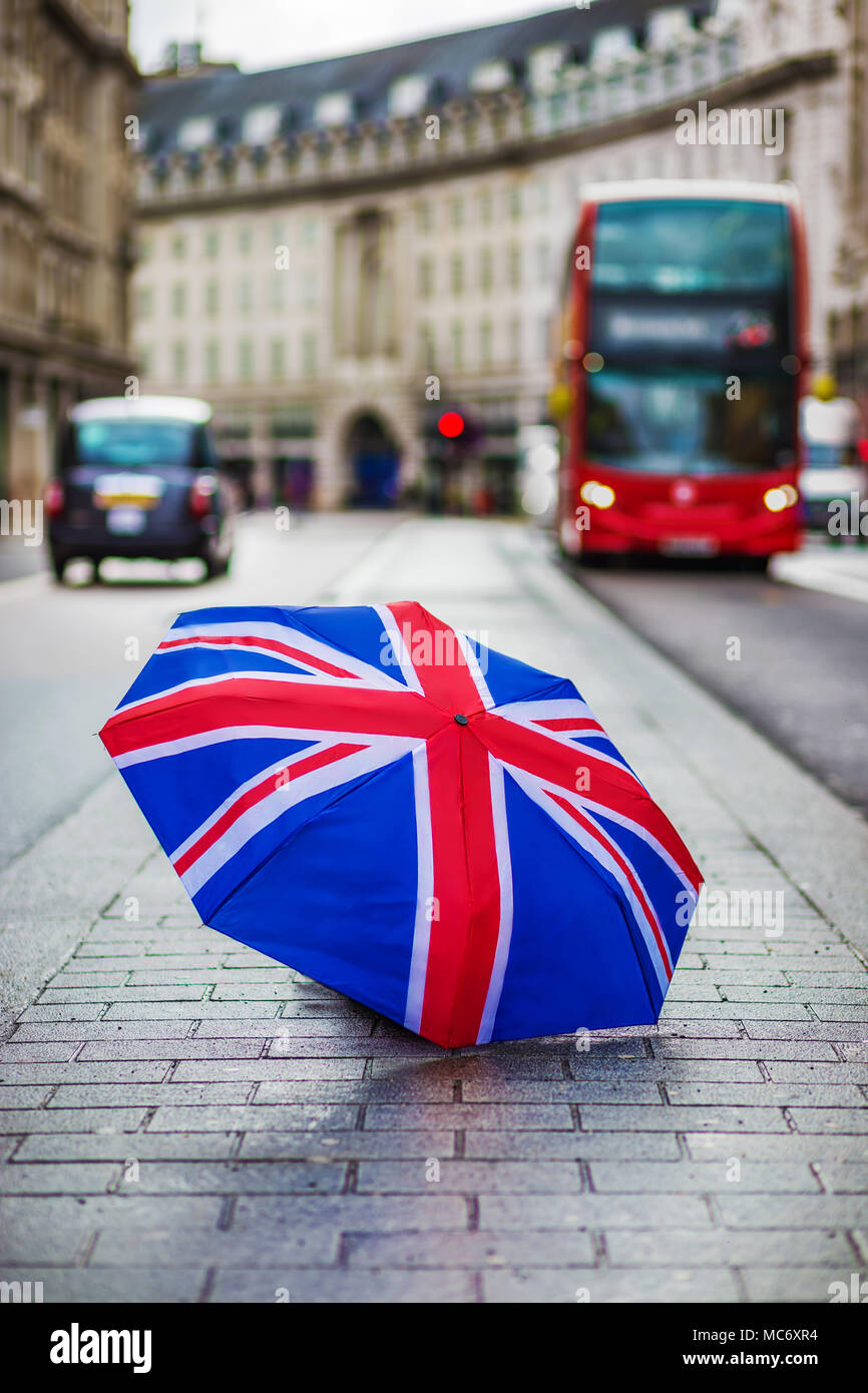 Londra, Inghilterra - British ombrellone al Regent Street con iconica red double-decker bus e taxi neri in movimento Foto Stock