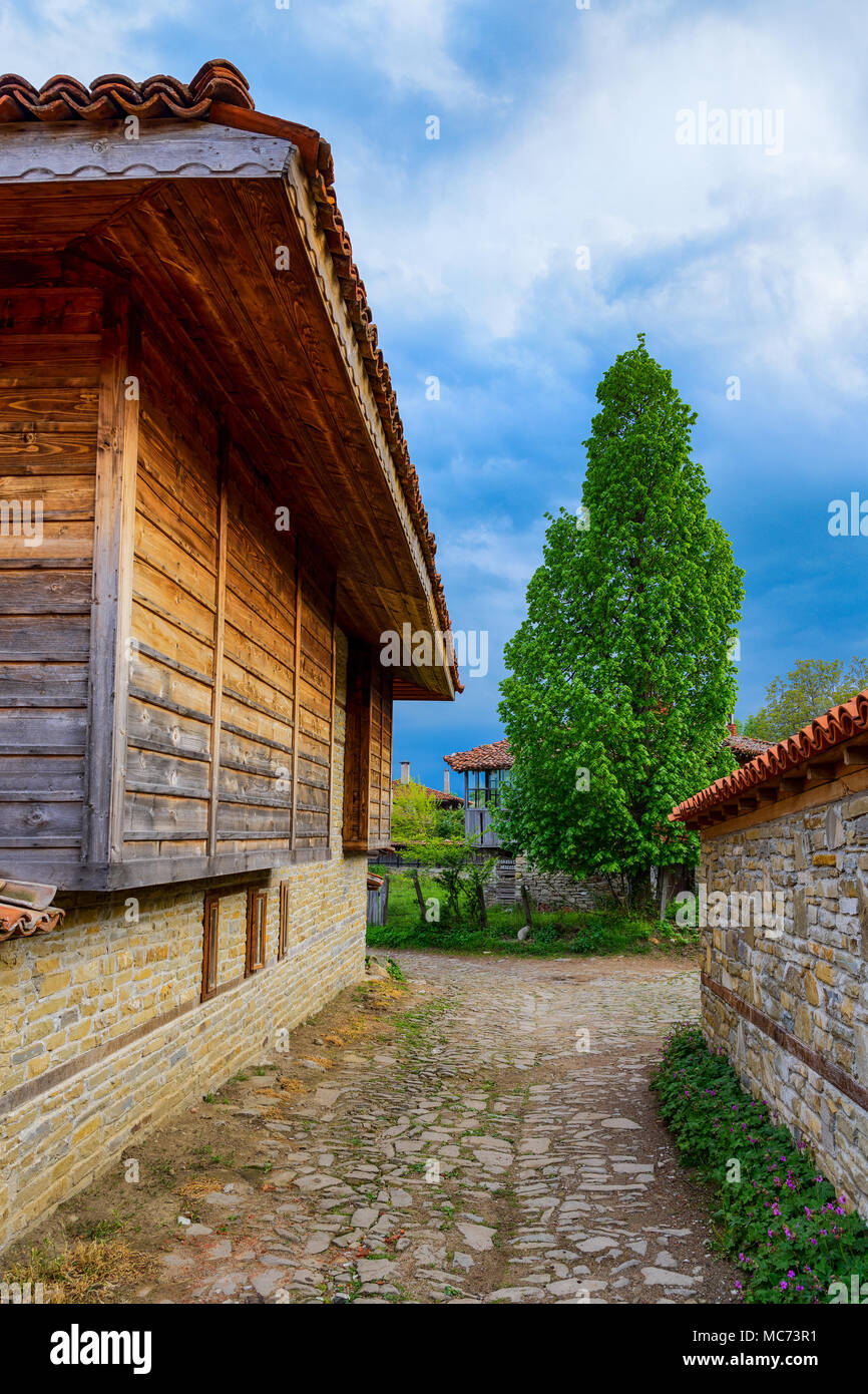 Stretta viuzza acciottolata in Zheravna, Bulgaria - riserva architettonica di case rustiche dalla nazionale bulgara per periodo di rinascita Foto Stock