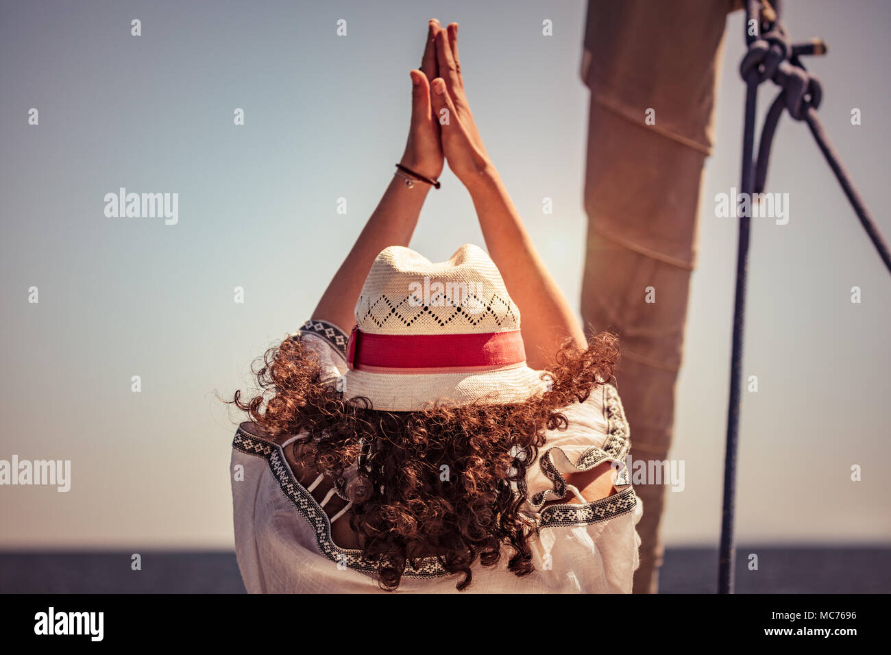 Donna facendo esercizi yoga, vista posteriore di una donna in piedi di Yoga asana sulla barca a vela tra mare, detersione di aura, meditando sulla vacanza Foto Stock