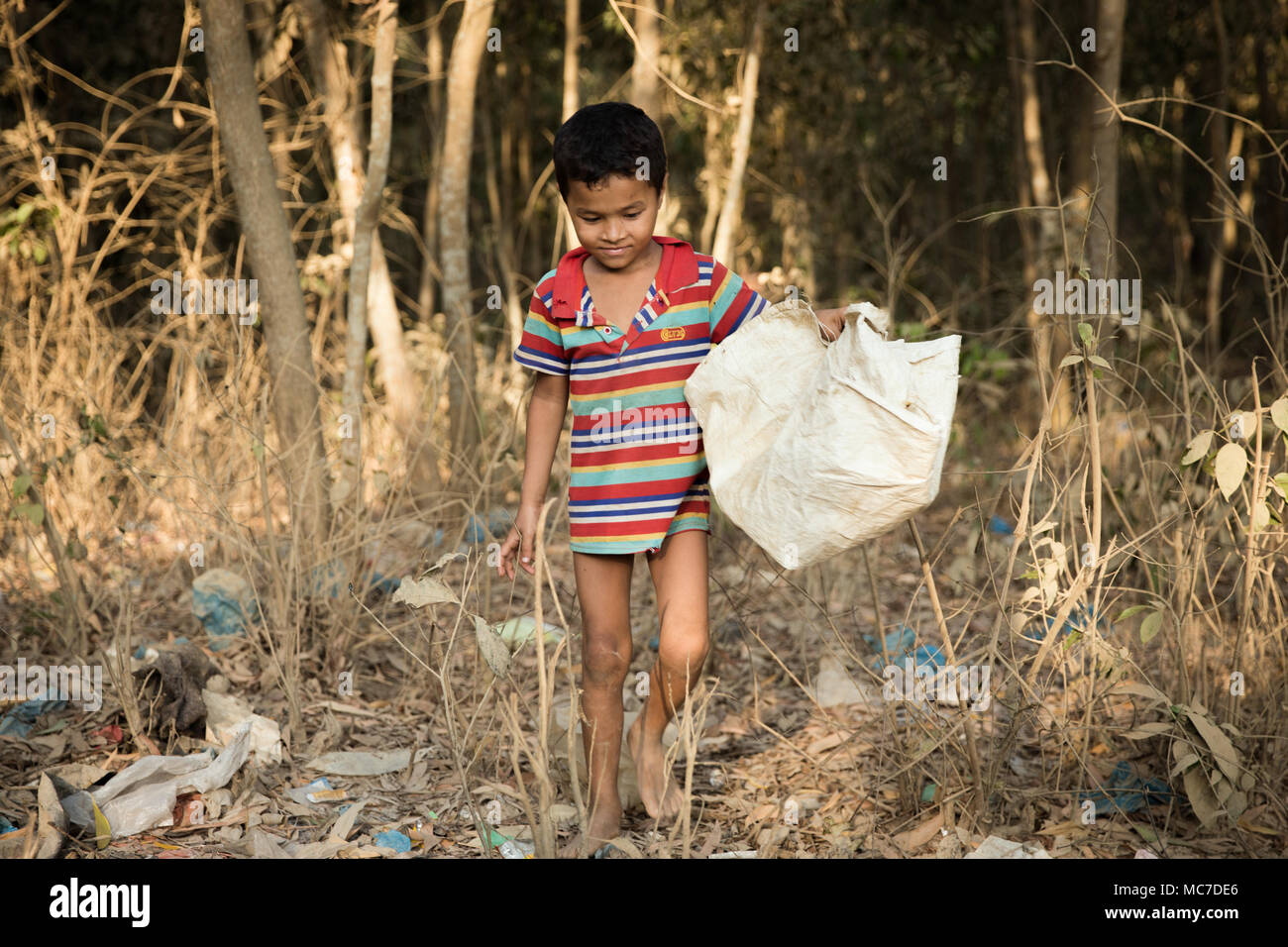 Un giovane ragazzo Rohingya passeggiate attraverso un bosco di spazzatura in Kutupalong Refugee Camp. Ora ci sono circa 600.000 rifugiati Rohingyas in Kutupalong campo profughi del sud del Bangladesh. Mentre i preparativi sono ormai essendo realizzato per la stagione dei monsoni che si sta avvicinando velocemente, molte ONG hanno lasciato lasciando molto lavoro da fare per rendere le loro insufficienze. Foto Stock