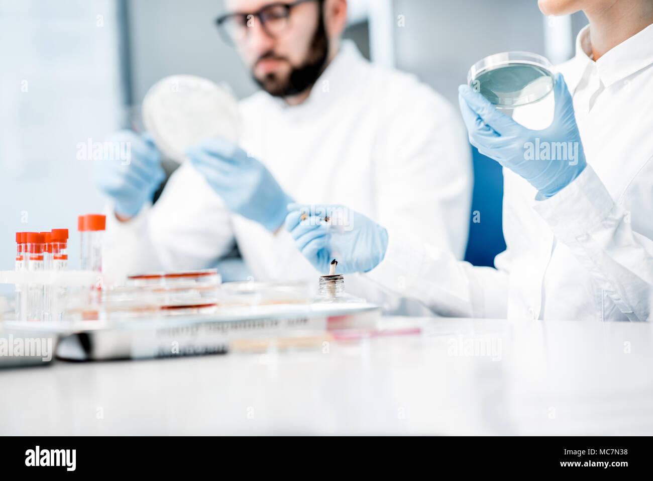 Paio di medici in uniforme facendo esami batteriologici in seduta il moderno laboratorio Foto Stock