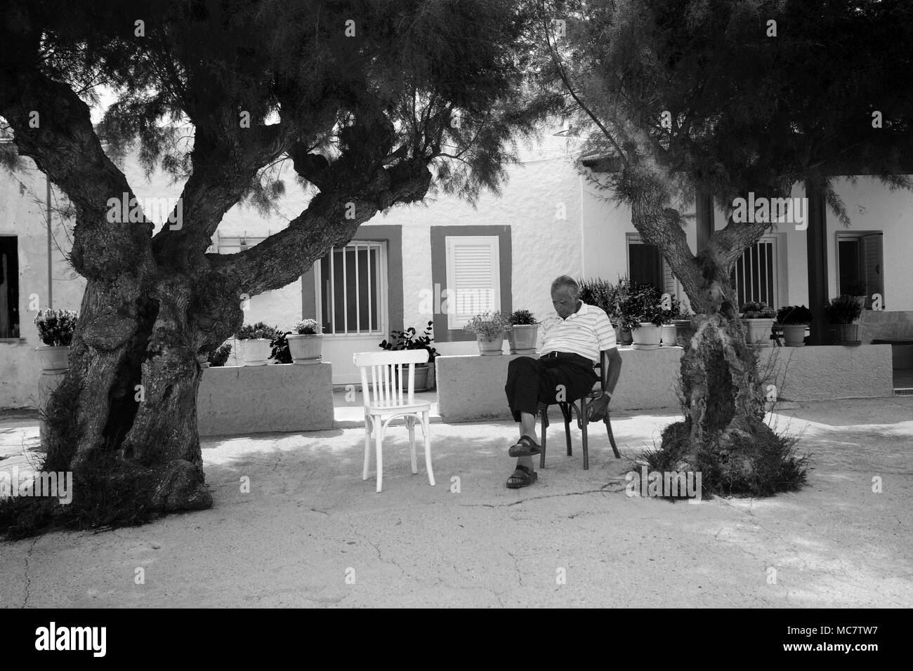L'uomo avente una funzione snooze nell'ombra di un due alberi, Rodi, Grecia Foto Stock