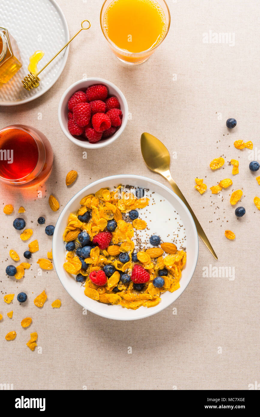 Vista dall'alto di una sana prima colazione. Fiocchi di mais con yogurt, mandorle, mirtilli e lamponi e semi di Chia. Servite con lo sciroppo di acero e succhi di frutta. Foto Stock