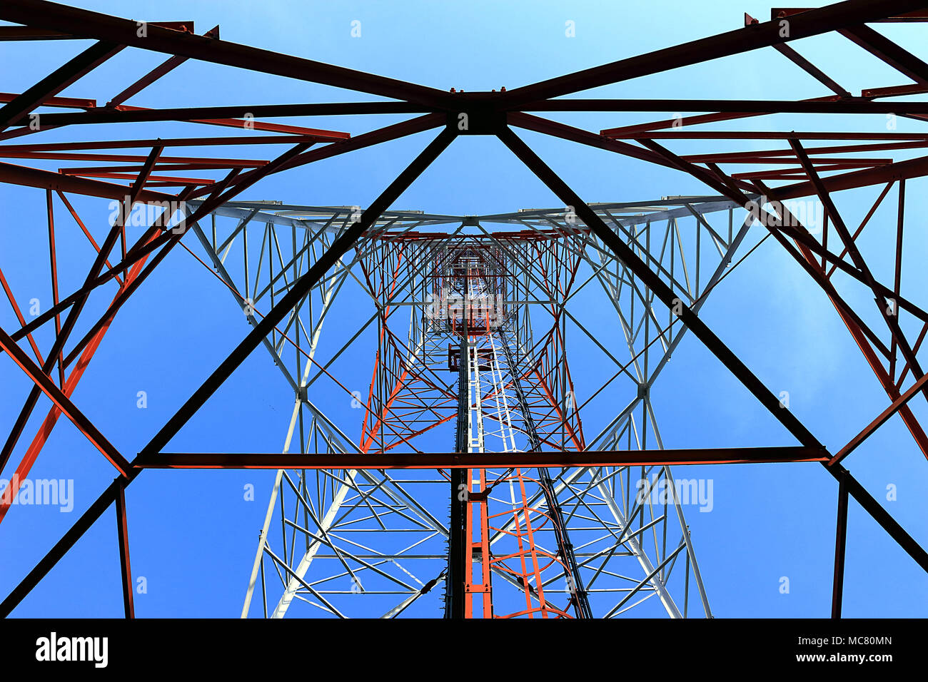 La fotografia offre una prospettiva verso l'alto della struttura interna di una torre di telecomunicazioni. L'immagine rivela la complessa struttura in acciaio che c Foto Stock