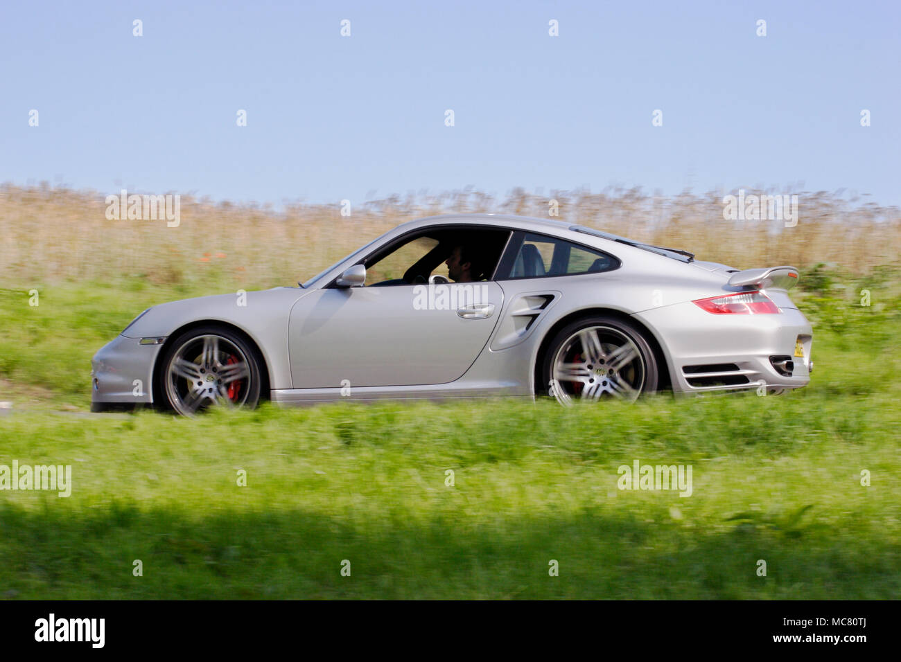 Angolo di basso profilo (vista laterale) di un argento Porsche 911 997 La guida veloce Foto Stock