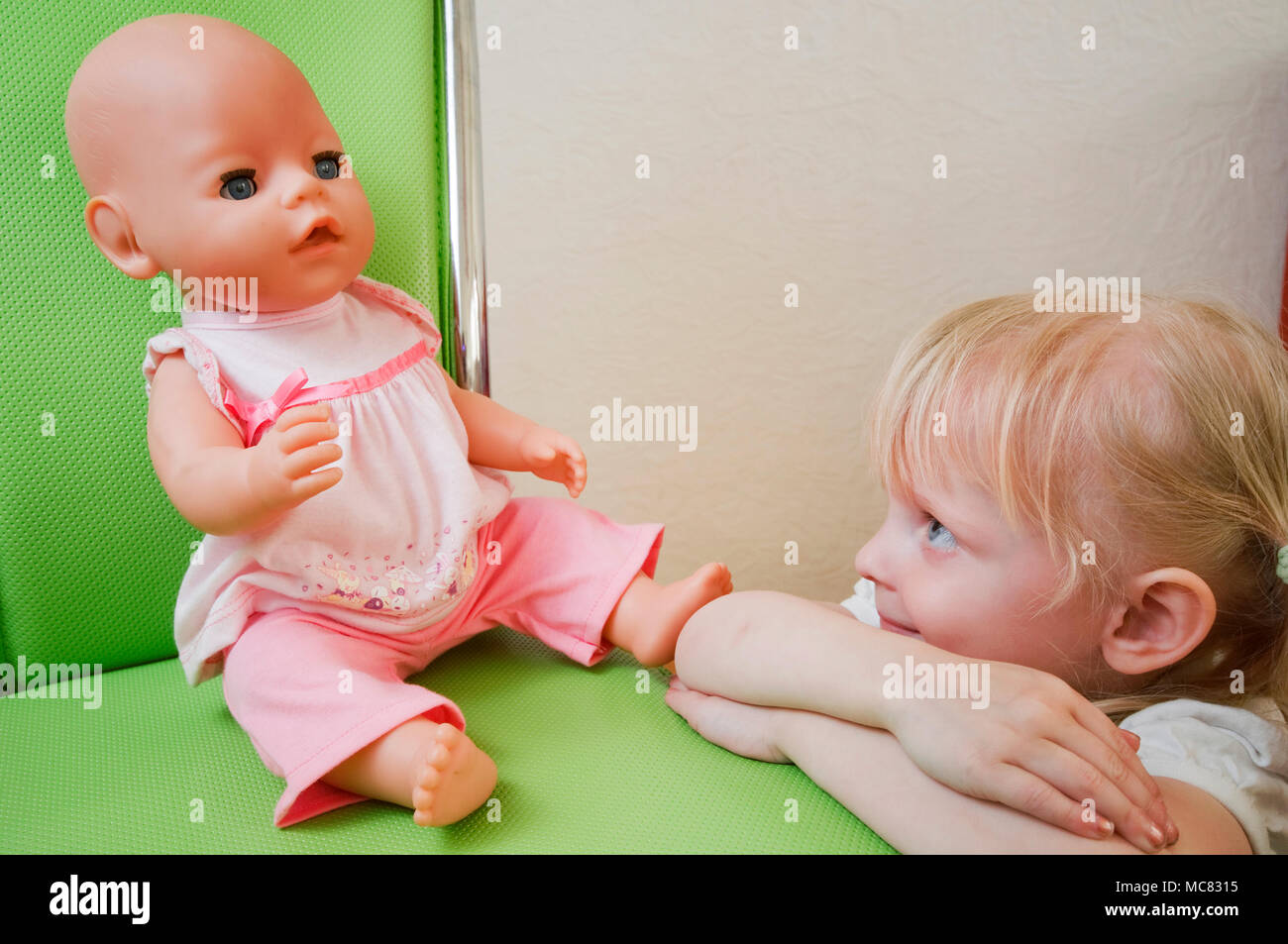 Laterali testa e spalle in vista di una scuola materna bambina cerca amorosamente a sua bambola. Foto Stock