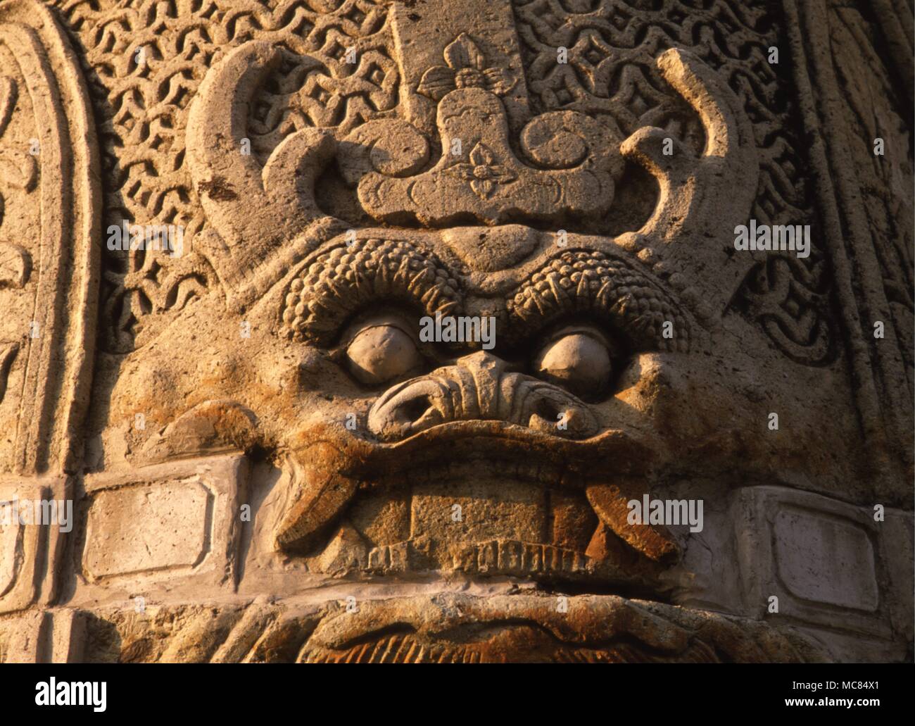 Il demone fanged, scolpito in pietra sul nastro decorativo di una guardiana del tempio di Wat Arun complessa, Bangkok. Foto Stock