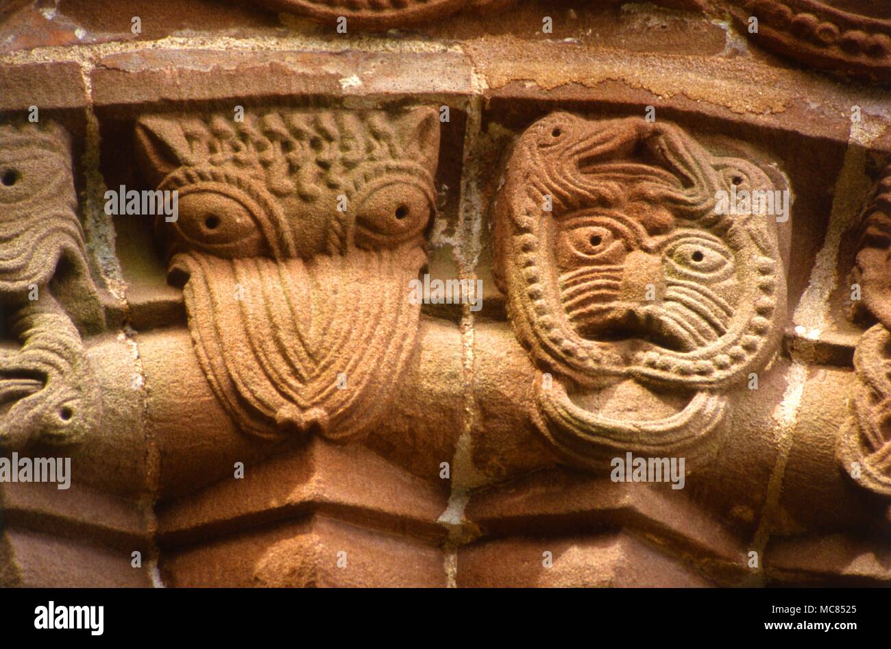 Facce demoniaco tra le sculture di epoca normanna sulla porta sud della chiesa a Kilpeck, vicino a Hereford. Foto Stock