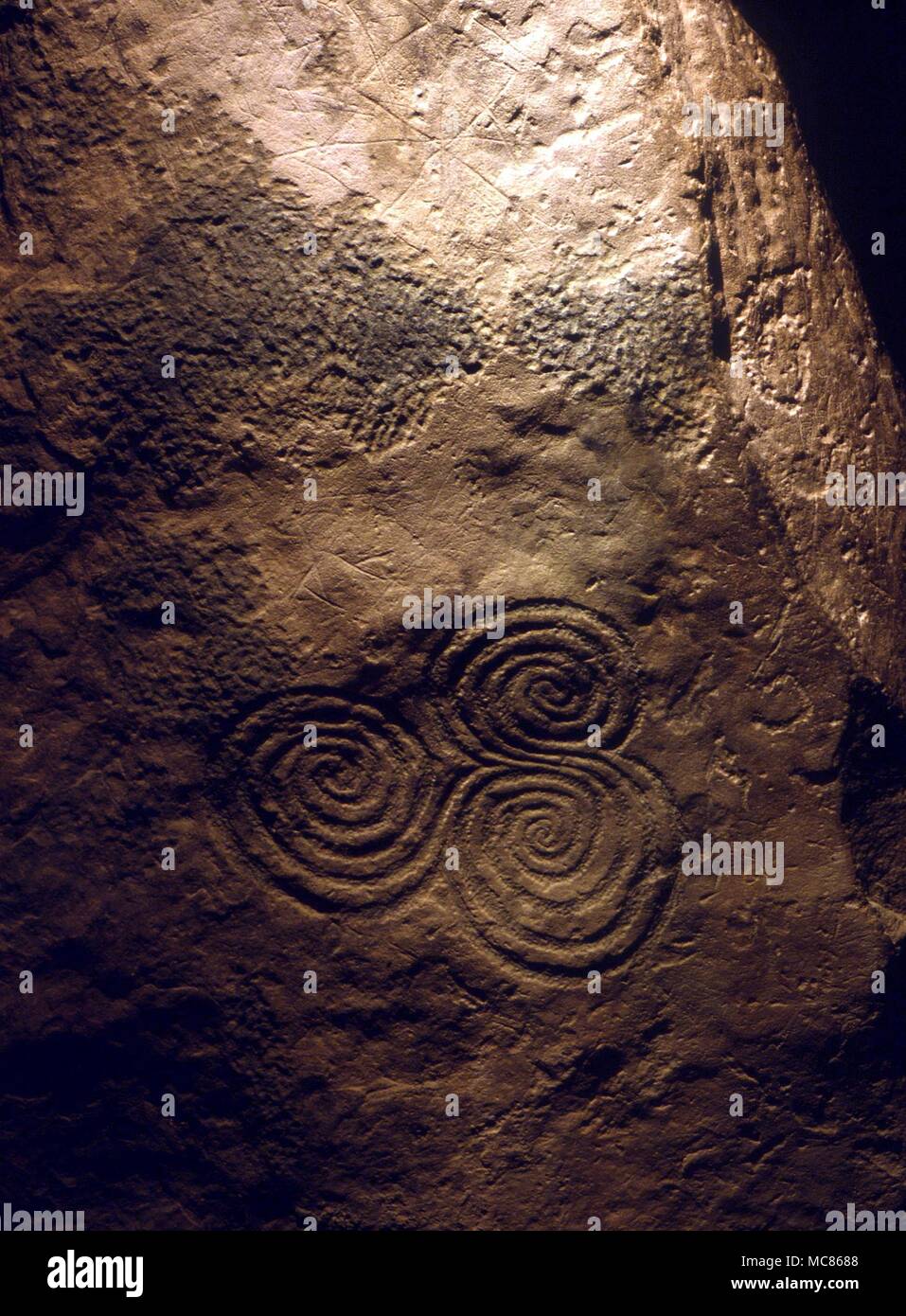 NEWGRANGE (KNOWTH) - Irish sito preistorico. Circa 3.000 BC. Spirale su pietra C10 il tri-spirale su pietra C10 alla fine del passaggio a Newgrange. Questa spirale è sempre nelle tenebre, ma è illuminato quando i raggi del sole penetrano a fondo del passaggio al winter soltice Foto Stock