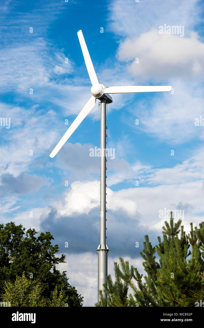 Energia pulita bianco turbina eolica in campo verde con piccoli alberi. Foto Stock