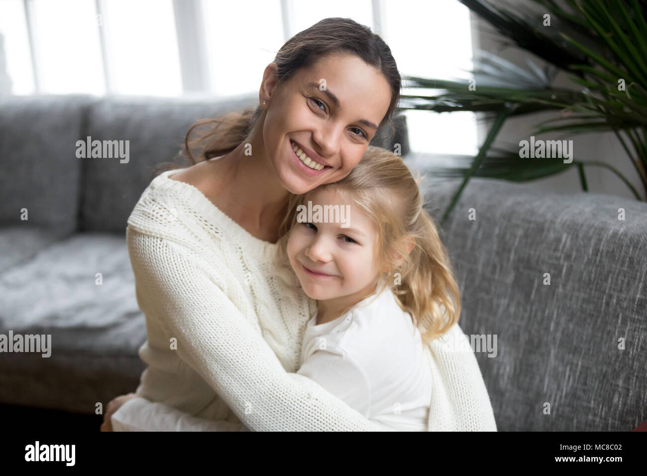 Ritratto di felice amorevole madre single abbracciando carino piccola figlia, sorridente giovane donna abbracciando in età prescolare ragazza di capretto, diverse mamma e bambino adottato l Foto Stock