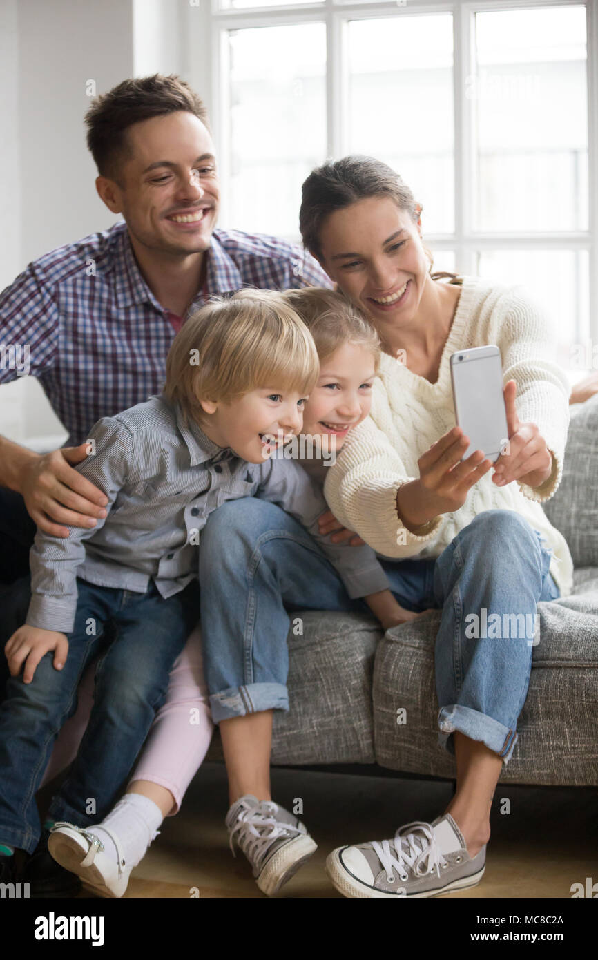 Felice madre tenendo famiglia selfie con mio marito e i ragazzi guardando smartphone, giocoso i bambini adottati i fratelli avendo divertimento che posano per una foto divertente su Foto Stock