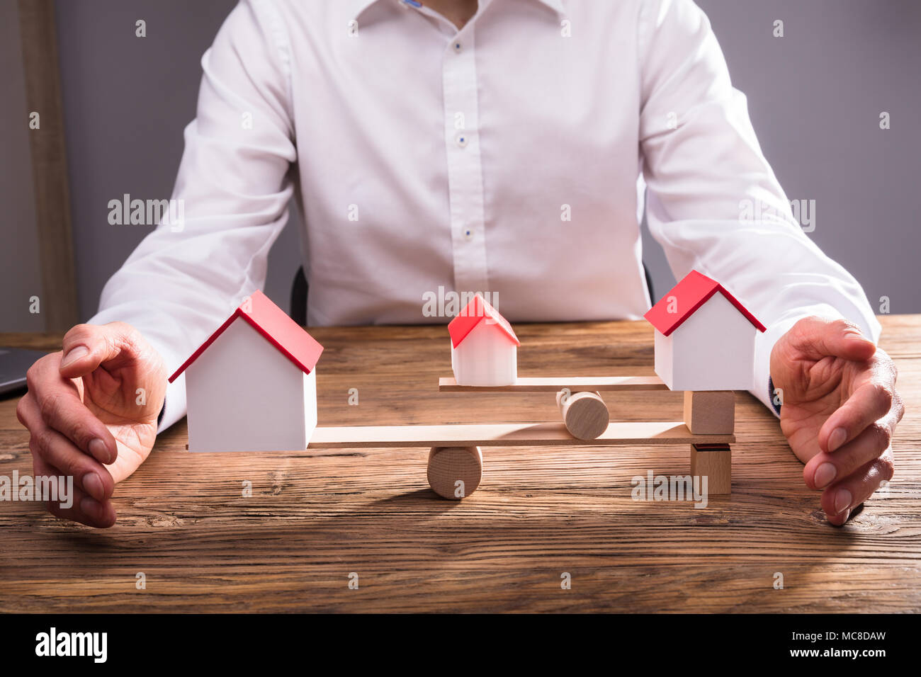 Close-up di commercianti la mano che copre l'equilibrio tra il modello di casa su altalena in Office Foto Stock