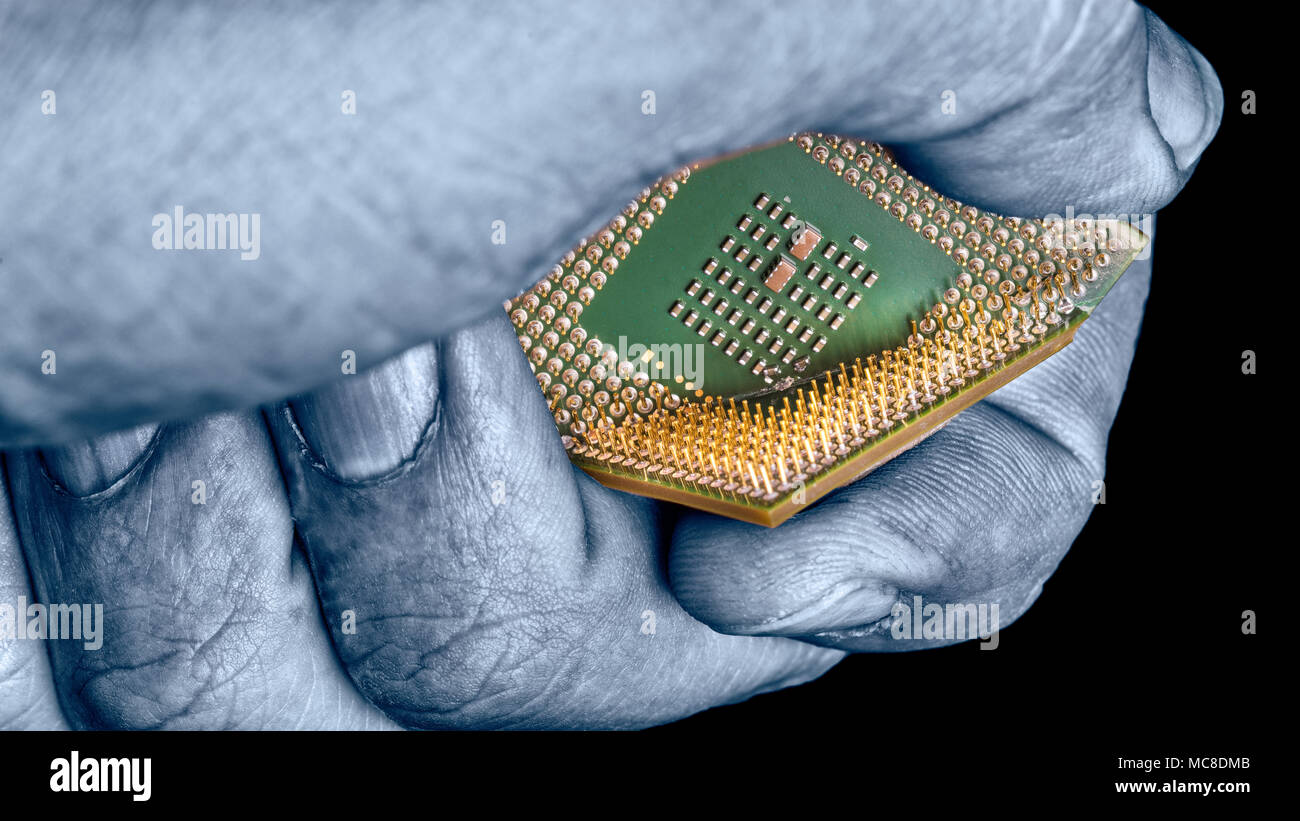 Mano misteriosa distrugge chip di computer con falla critica. Close-up di processore rotto in esperto le dita su sfondo nero. Spionaggio, idea di hacking. Foto Stock