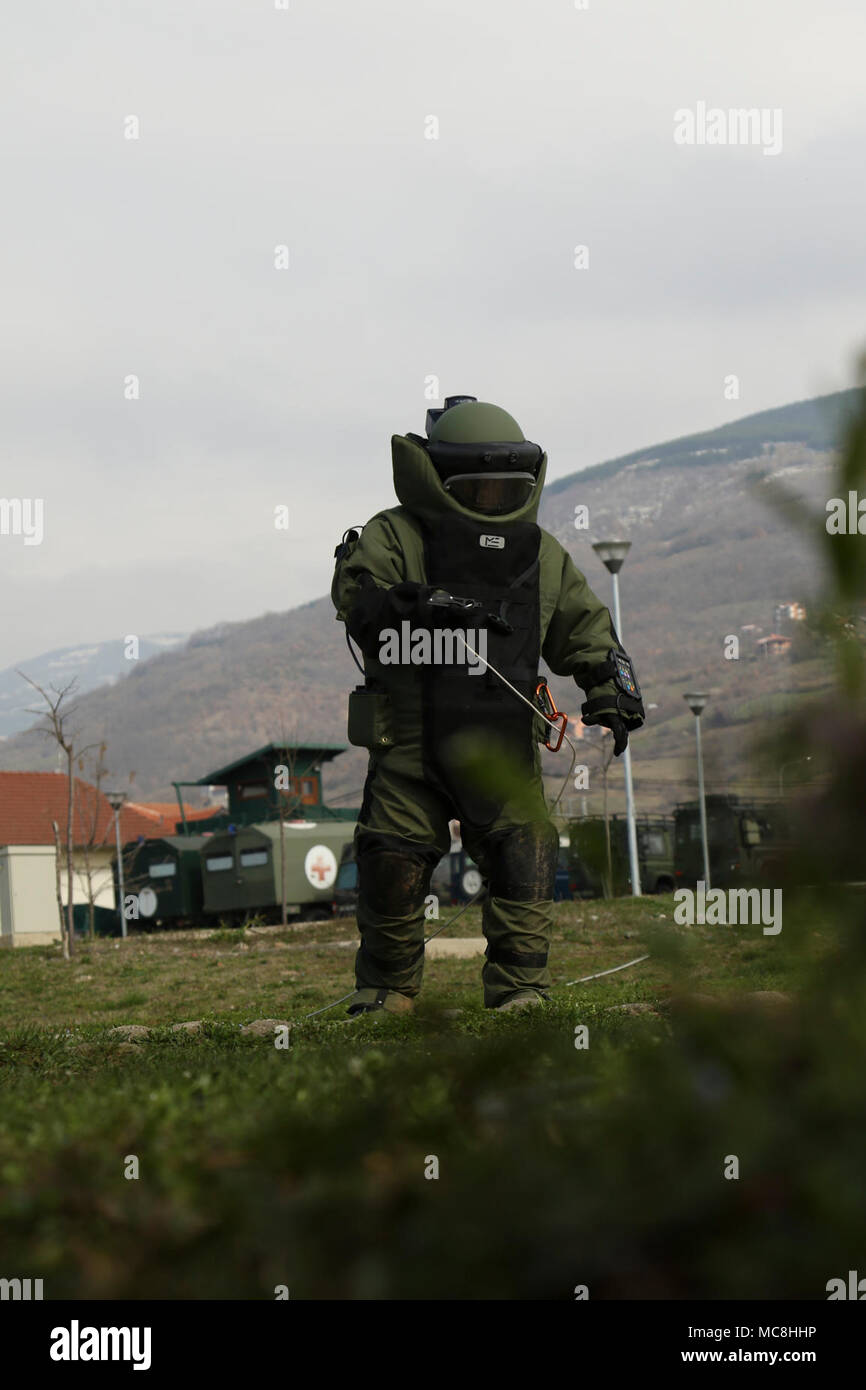 Un soldato dal Kosovo delle forze di sicurezza (KSF) cammina verso ordigni inesplosi in un'eliminazione degli ordigni esplosivi (EOD) suit durante uno scenario-based training evento condotto Mar. 26. Modulo di soldati del 702nd Ordnance Company, xvi truppe speciali battaglione, sedicesima brigata di supporto utilizzare le proprie conoscenze e la propria esperienza per aiutare a consigliare e assistere il KSF. Foto Stock
