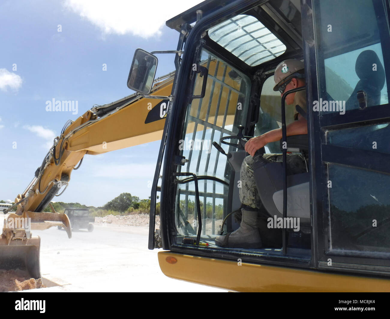 NORTHWEST FEILD, Guam (25 marzo 2018) Attrezzatura operatore Constructionman Jared pneumatico, assegnato alla Naval Mobile Battaglione di costruzione (NMCB) 11, Distacco Guam, rimuove lo sporco e detriti in un cratere durante una joint-service aviosuperficie rapida battaglia riparazione di danni di esercizio con la forza dell'aria. NMCB-11 è distribuito per eseguire la costruzione, umanitari e di assistenza estera, il teatro e la cooperazione in materia di sicurezza nel VII flotta area di operazioni. Foto Stock