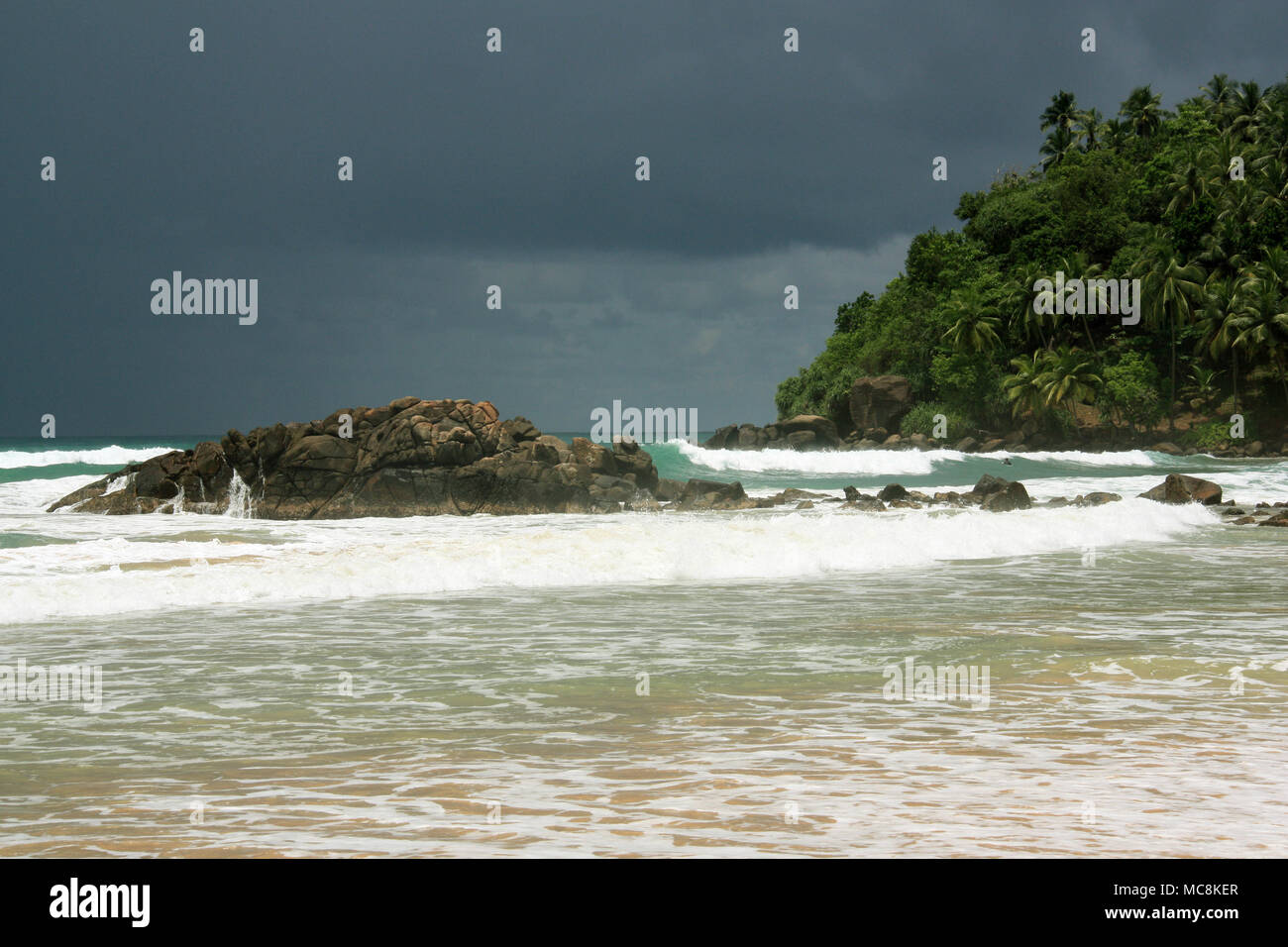 Spiaggia di Mirissa, Sri Lanka: Turquois acqua, sabbia fine, onde per il surf, sparse con splendide rocce e rivestiti con palme da cocco. Paradiso! Foto Stock
