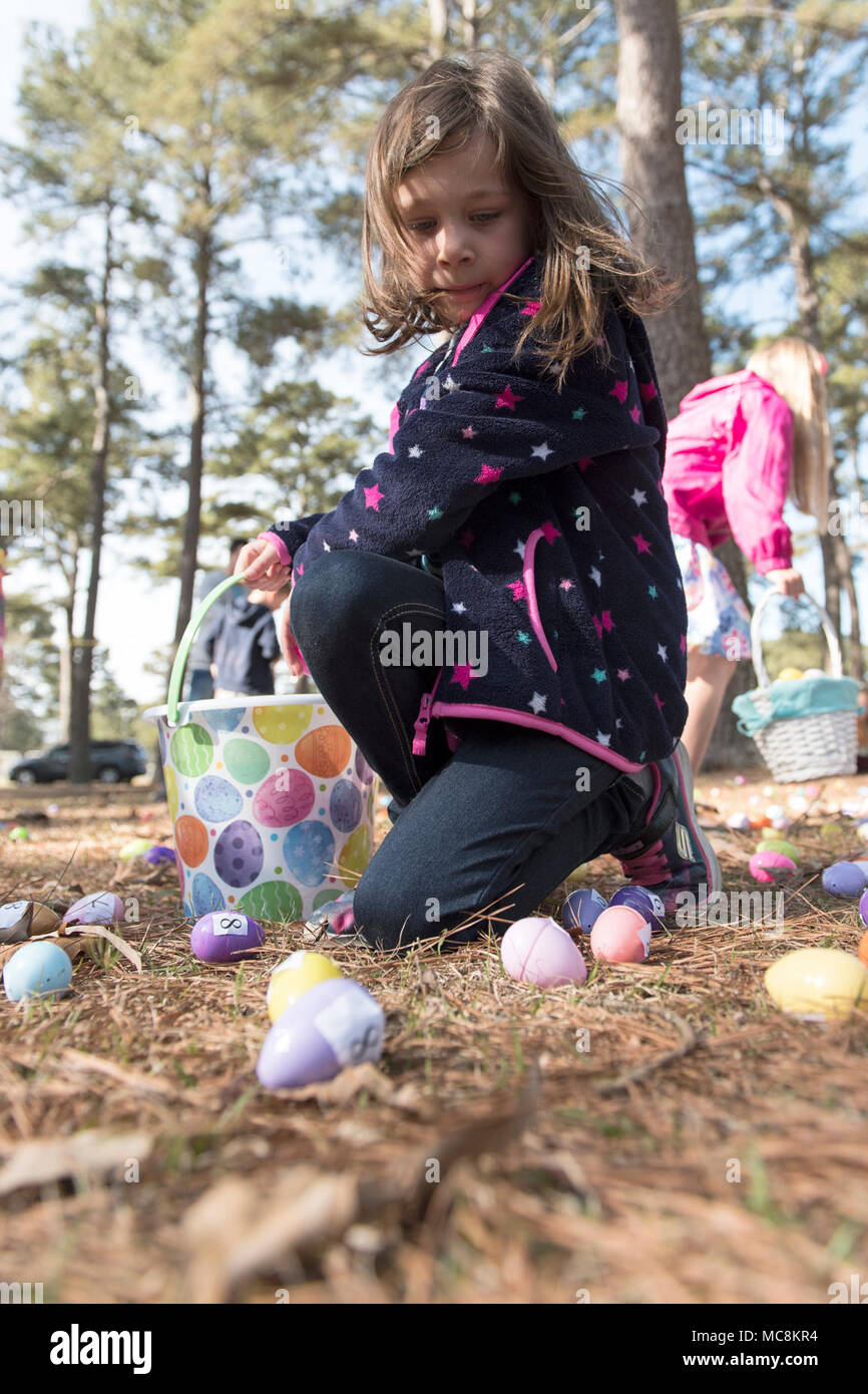 Emma, 7, raccoglie le uova durante la Pasqua giochi presso il centro giovanile su Seymour Johnson Air Force Base in North Carolina, Marzo 31, 2018. L'Uovo di Pasqua Caccia era diviso in quattro gruppi di età compresa da 1 a 12 anni di età. Foto Stock
