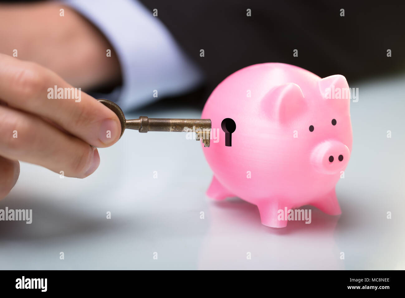 Close-up di mano di una persona chiave di inserimento nel salvadanaio di toppa di chiave Foto Stock