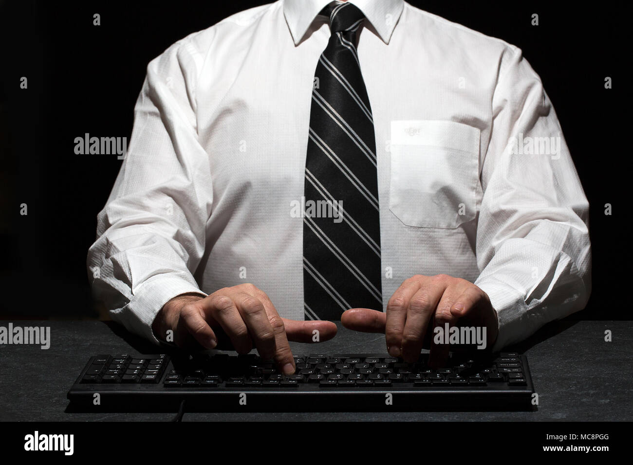 Uomo che indossa una camicia bianca con cravatta nera ha strisce su di esso durante la digitazione Foto Stock
