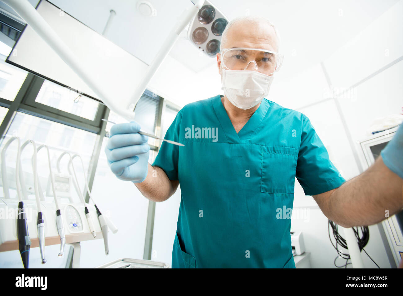 Coperta da un guanto dentista o chirurgo in maschera, occhiali e uniforme guardando il paziente prima della somministrazione orale del check-up Foto Stock