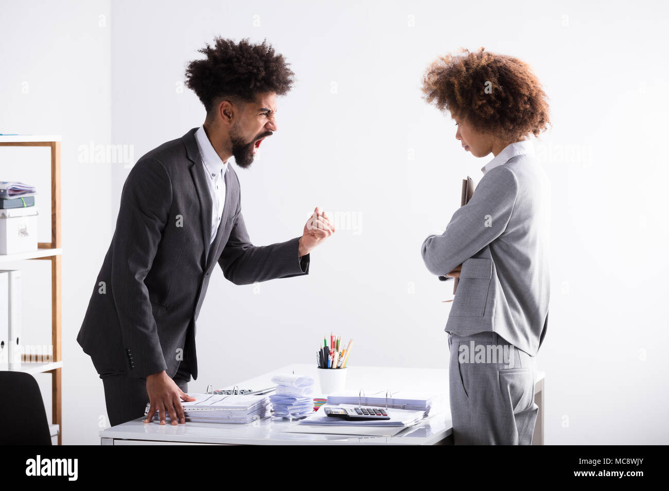 Angry Young Imprenditore gridava a femmina In Executive Office Foto Stock