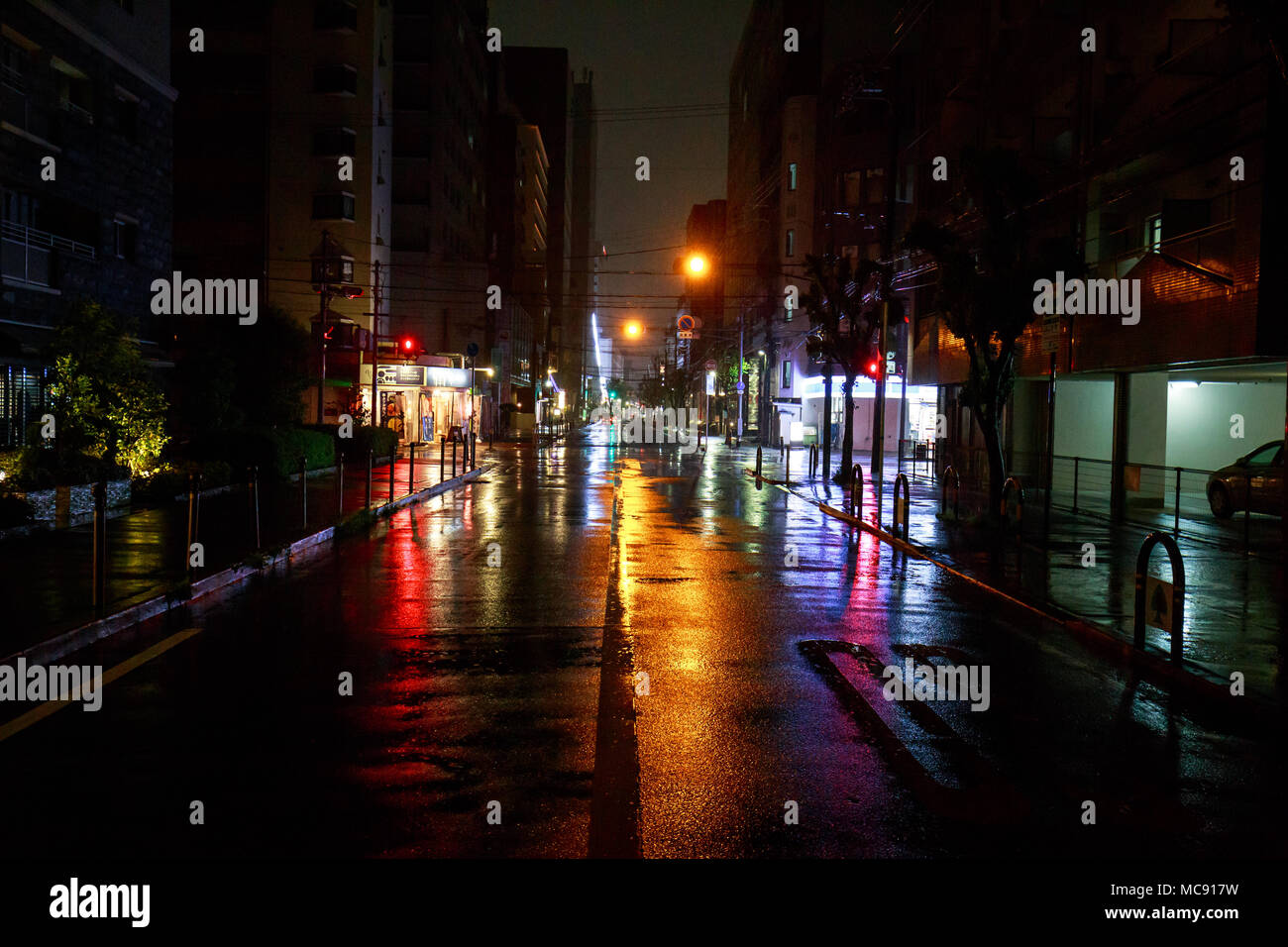 Osaka, Giappone - 14 Aprile 2018: le luci gialle riflettendo su un vuoto di mezzanotte street durante una pioggia pesante Foto Stock