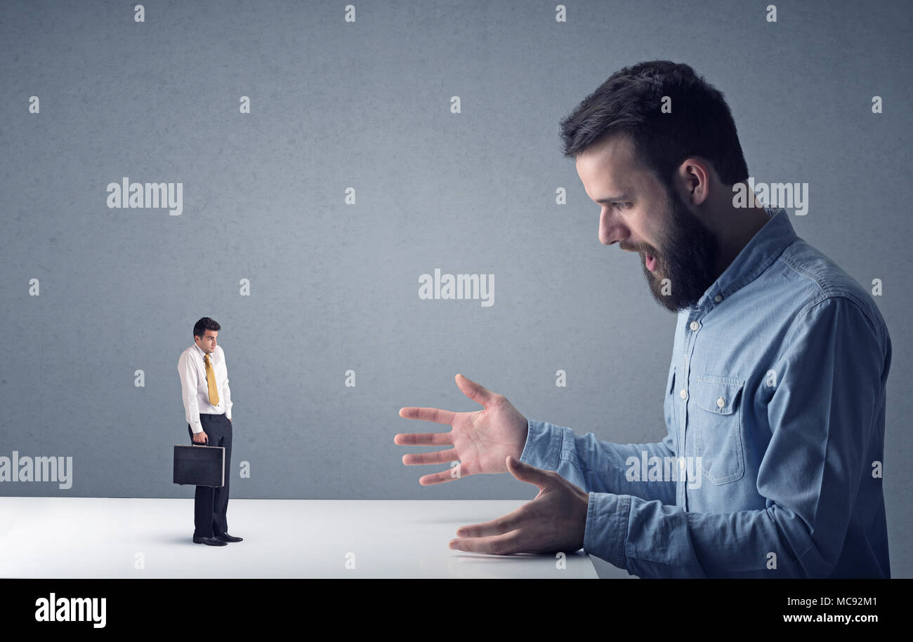 Giovane imprenditore professionale essendo arrabbiato con un altro imprenditore in miniatura Foto Stock