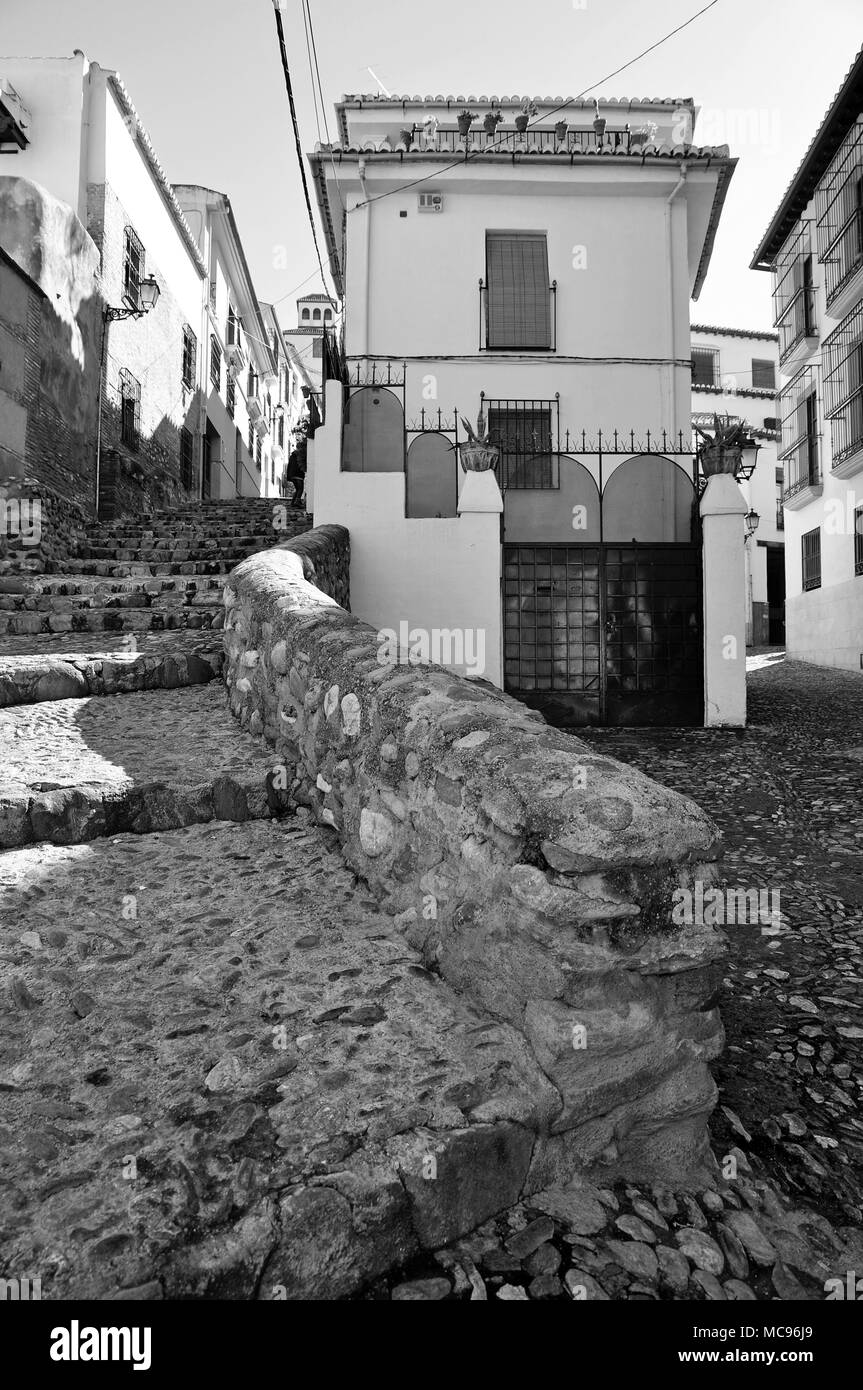 Vecchia strada medievale con pavimentazione in pietra e le scale e il bianco tipico vecchie case all'Albaicín quartiere arabo di Granada (Andalusia, Spagna) Foto Stock