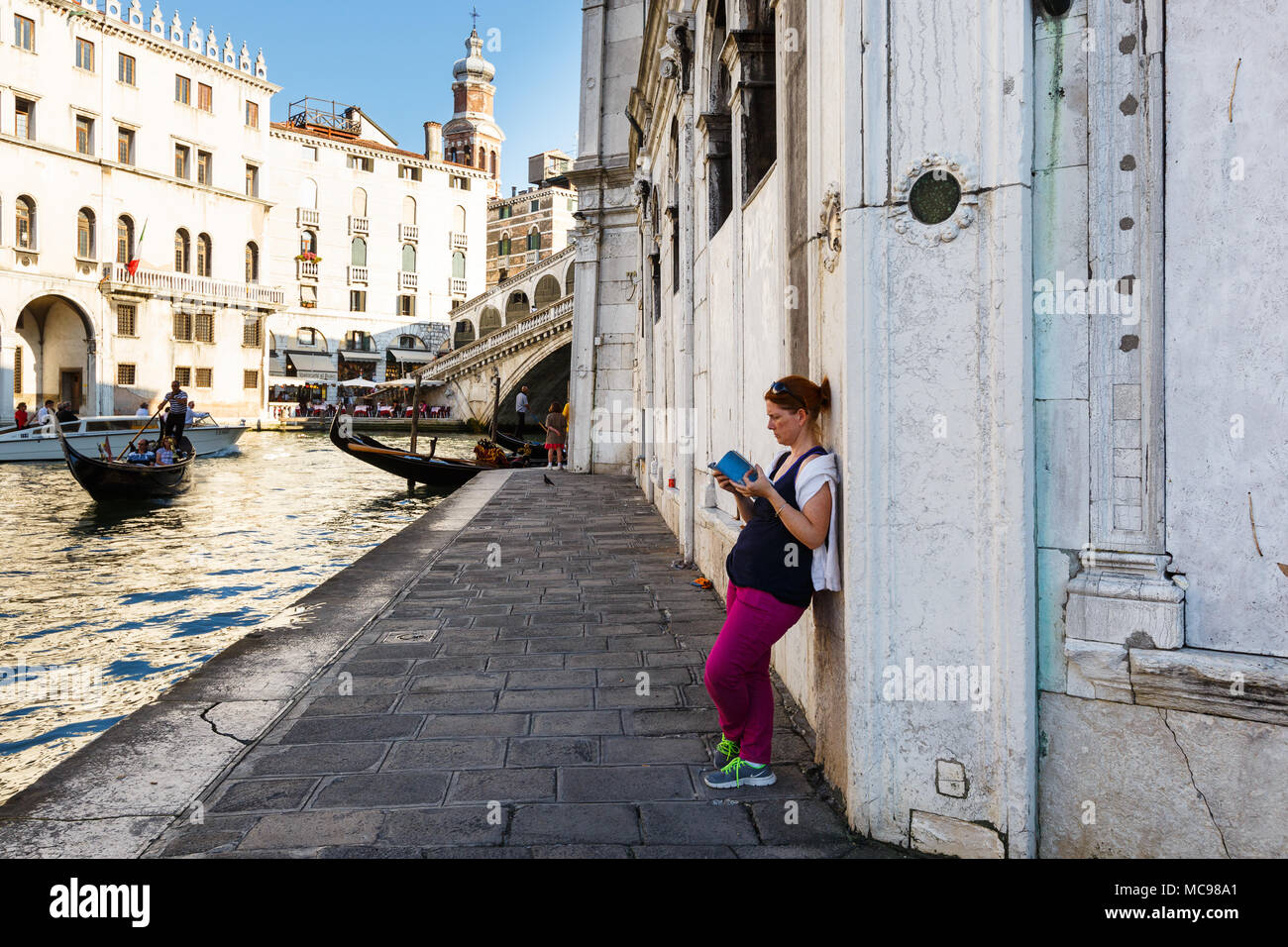 Venezia, Italia - Giugno, 21, 2013: Vista della gondola e il Ponte di Rialto, molti turisti su un ponte, donne legge un libro all'ombra, il campanile della chiesa Foto Stock
