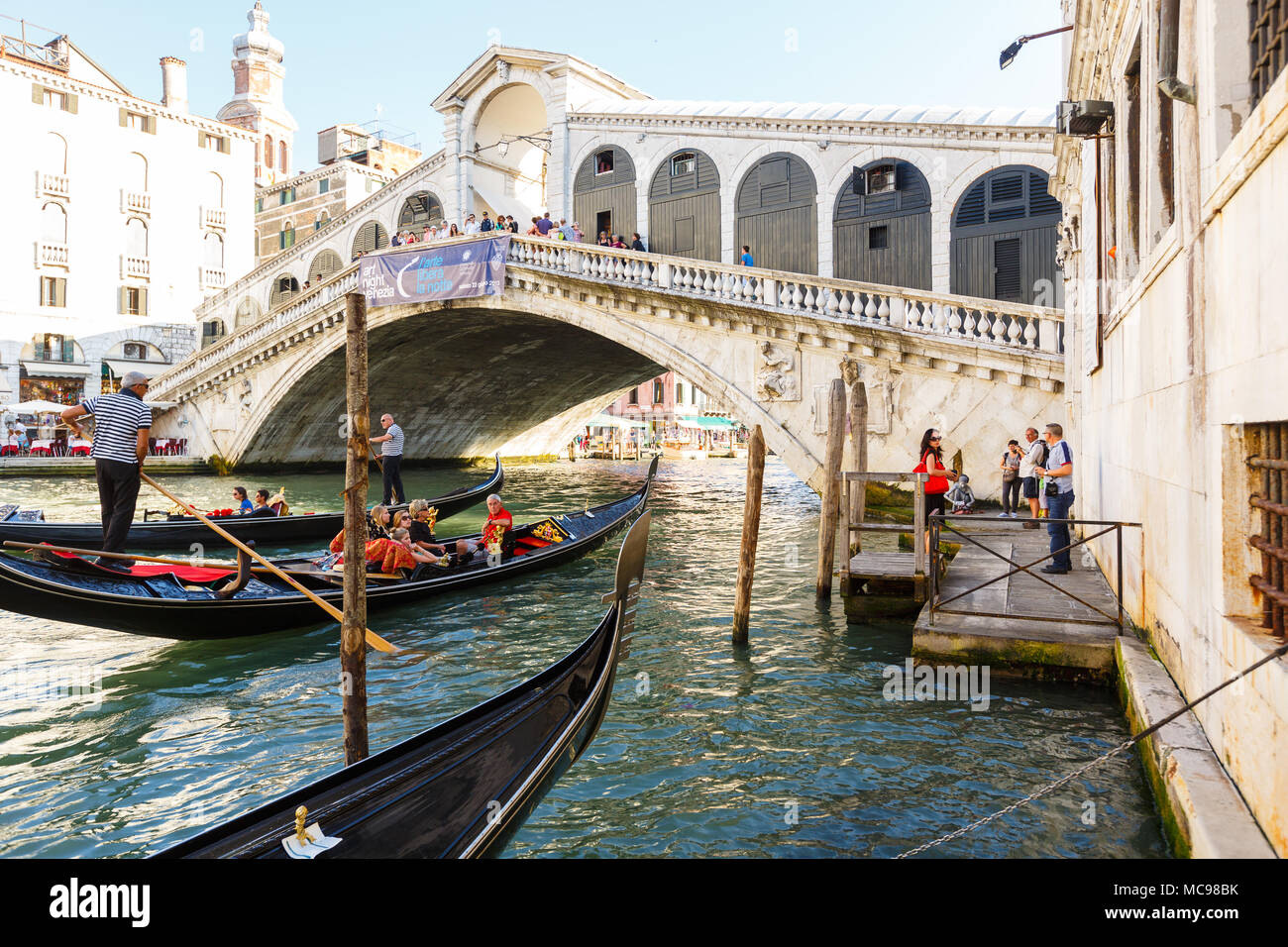 Venezia, Italia - Giugno, 21, 2013: Vista di gondole con passenges e il Ponte di Rialto, molti turisti su un ponte, , openair ristorante con ombrelloni su Foto Stock