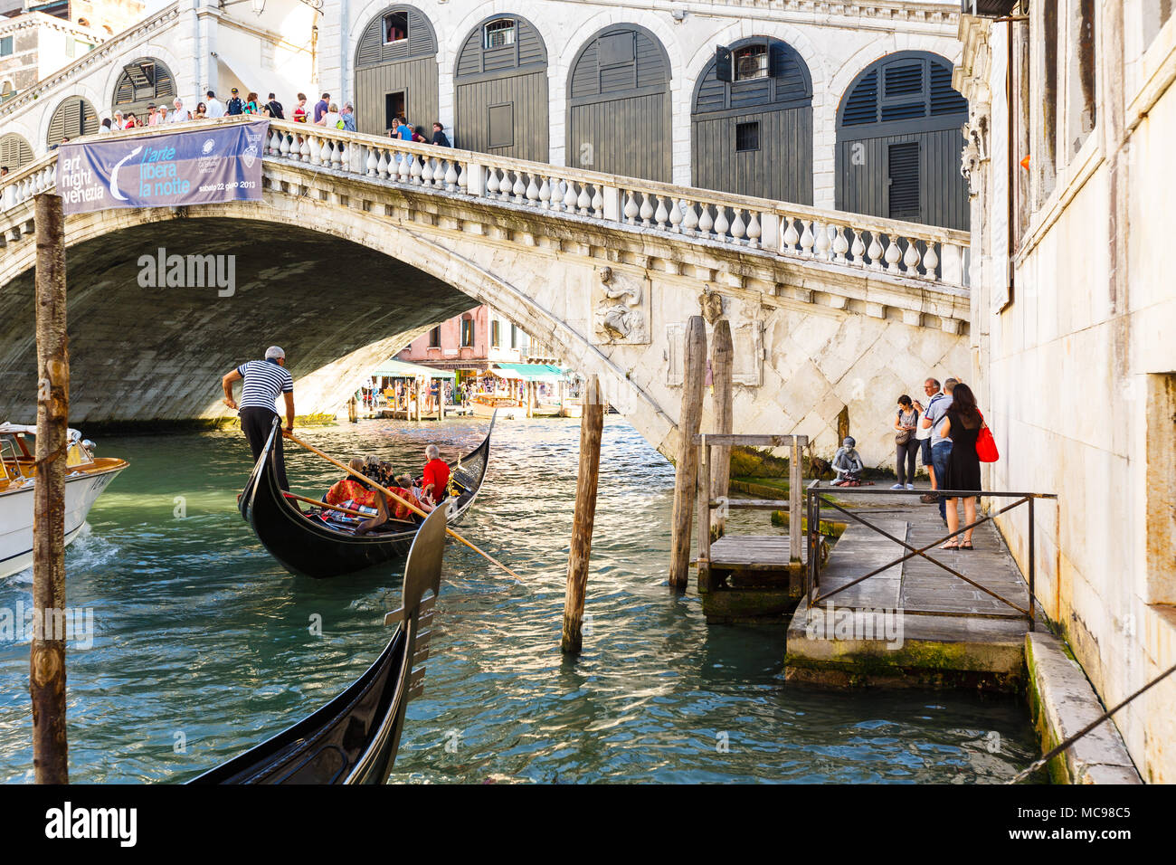 Venezia, Italia - Giugno, 21, 2013: Vista della gondola sul Canal Grande e sul Ponte di Rialto, molti turisti su un ponte, la gente a restare in prossimità dell'acqua. Sunny summe Foto Stock