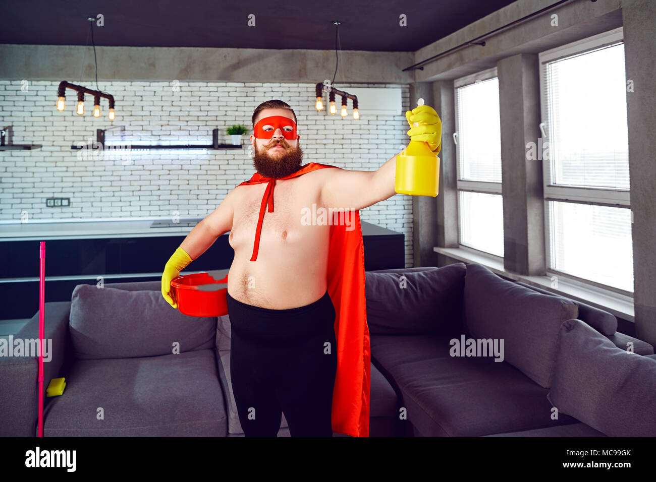 Un grasso, funny man in un costume da supereroe è la pulizia della casa.  Cleaner è un super eroe nell'appartamento Foto stock - Alamy