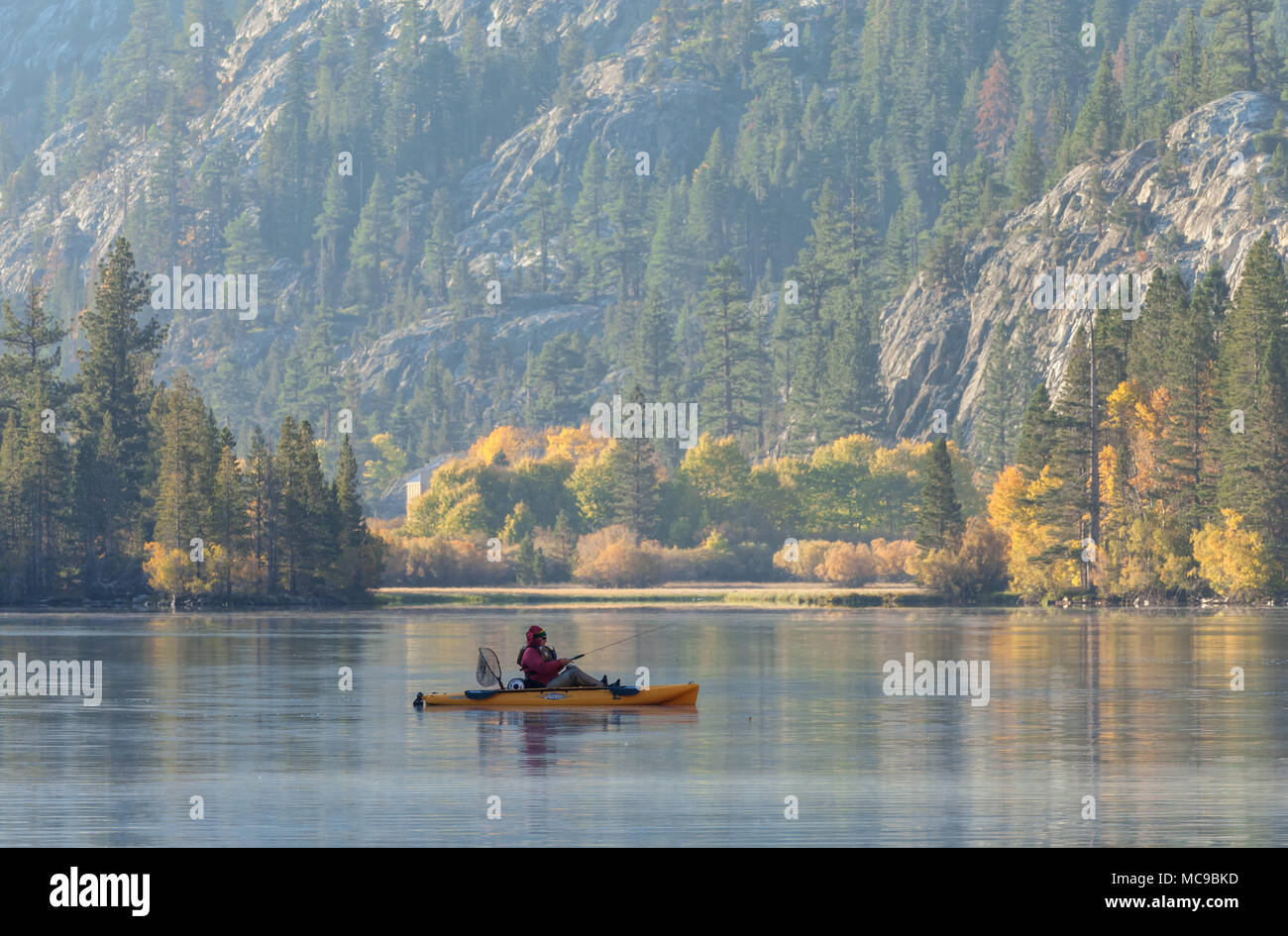 Un pescatore è stato il canottaggio nel Lago d'argento su un inizio autunno mattina, Giugno Lago di Loop, Giugno Lago, California, Stati Uniti. Foto Stock