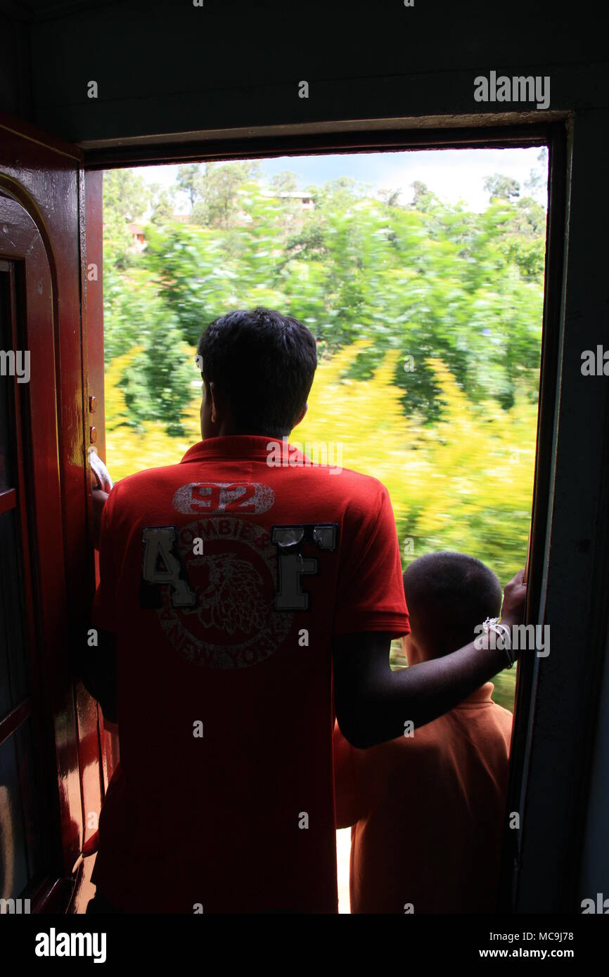 Un panoramico giro in treno da Ella a Kandy, passando alcuni paesaggi mozzafiato. Due uomini stavano in piedi nell'aprire lo sportello del carrello. Foto Stock
