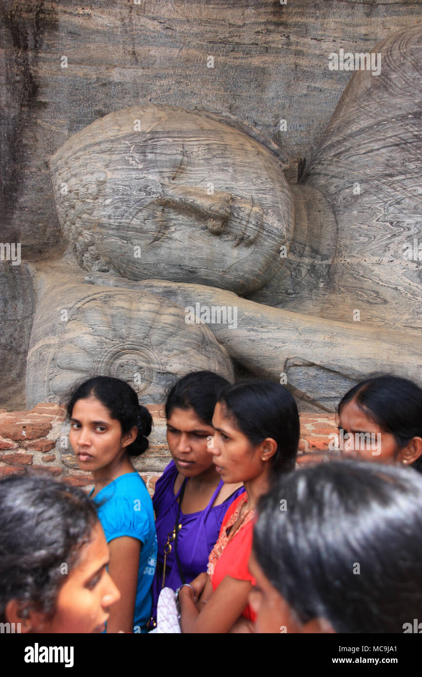 Indiano o dello Sri Lanka pellegrini di fronte a un gigante Buddha reclinato statua nella royal antica città di Polonnaruwa in Sri Lanka Foto Stock