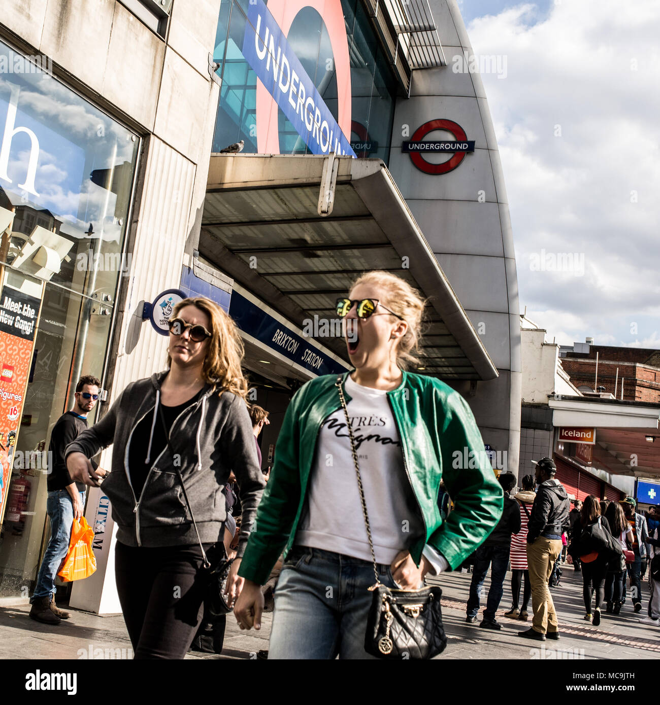 Due donne gente che camminava davanti all'entrata della Brixton stazione della metropolitana nella zona sud di Londra, Regno Unito Foto Stock