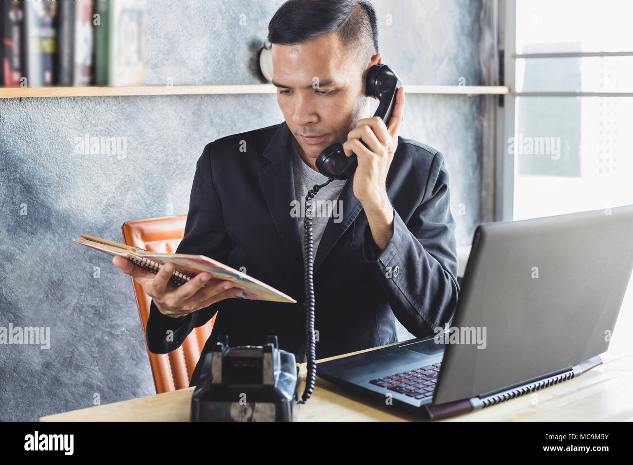 Sales Assistant presso la casa editrice a parlare con il cliente al telefono e alla ricerca data di prenotazione nota Foto Stock