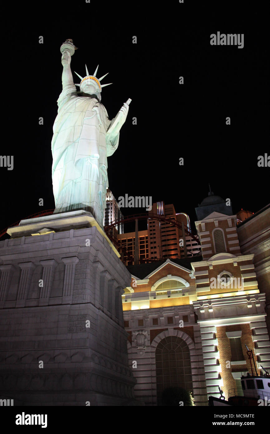 Vista la accesa la Statua della Libertà replica nella parte anteriore del artificiale dello skyline di New York e il rollercoaster del New York-New York, Las Vegas, NV, STATI UNITI D'AMERICA Foto Stock
