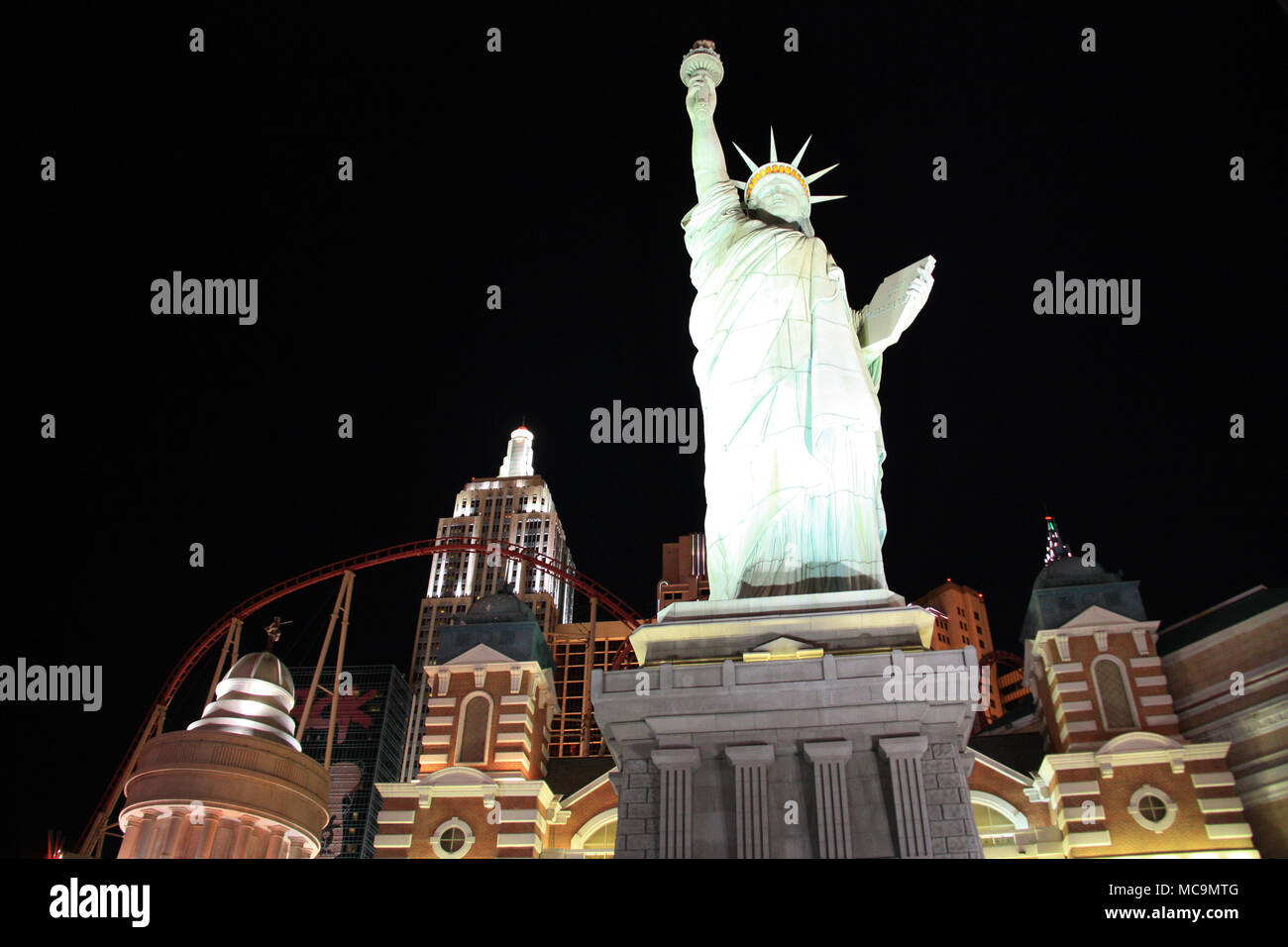 Vista la accesa la Statua della Libertà replica nella parte anteriore del artificiale dello skyline di New York e il rollercoaster del New York-New York, Las Vegas, NV, STATI UNITI D'AMERICA Foto Stock