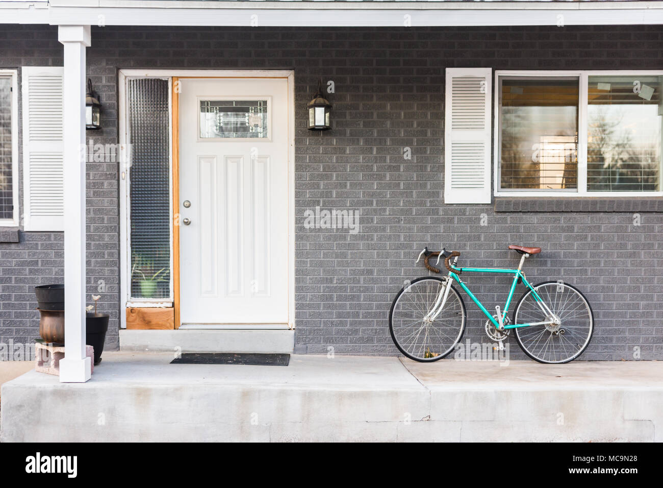 Portico frontale di grigio grigio casa di mattoni con moto parcheggiate Foto Stock