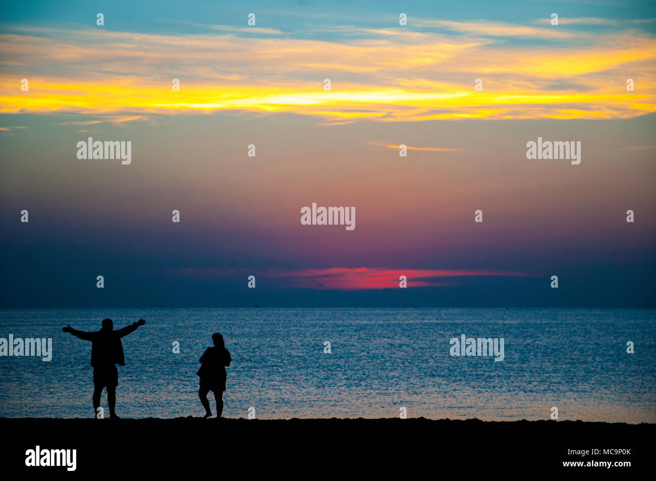 Un paio di persone stagliano contro la mattina Florida Sunrise presso la spiaggia. Foto Stock