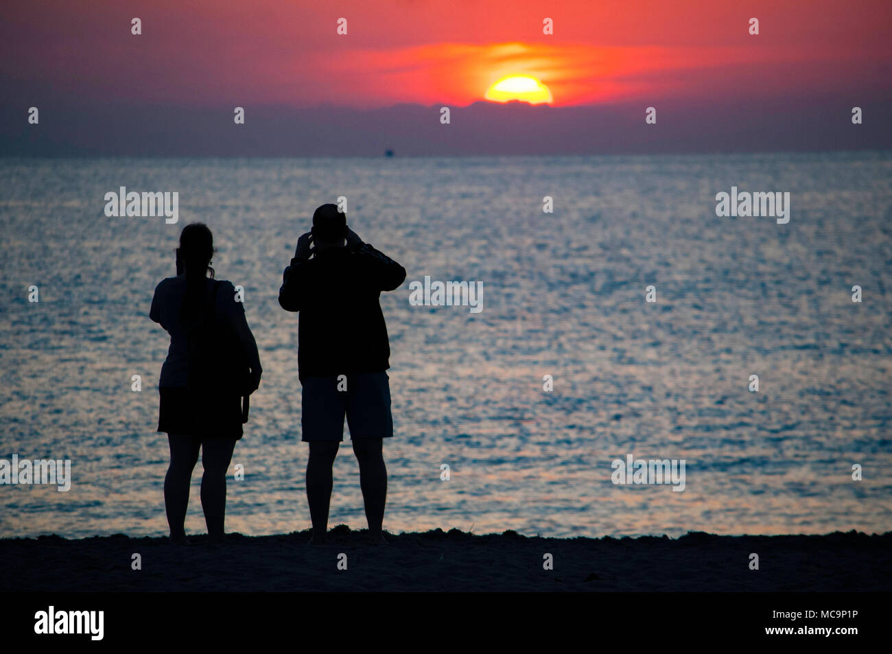 Un paio di persone stagliano contro la mattina Florida Sunrise presso la spiaggia. Foto Stock
