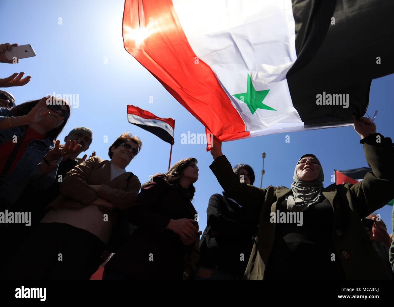 (180414) -- AMMAN, Aprile 14, 2018 (Xinhua) -- manifestanti onda bandiere siriano durante una manifestazione di protesta a seguito di una ondata di Stati Uniti, inglesi e francesi di scioperi militare sulla Siria di fronte all ambasciata americana ad Amman, Giordania, 14 aprile 2018. (Xinhua/Mohammad Abu Ghosh) (SWT) Foto Stock