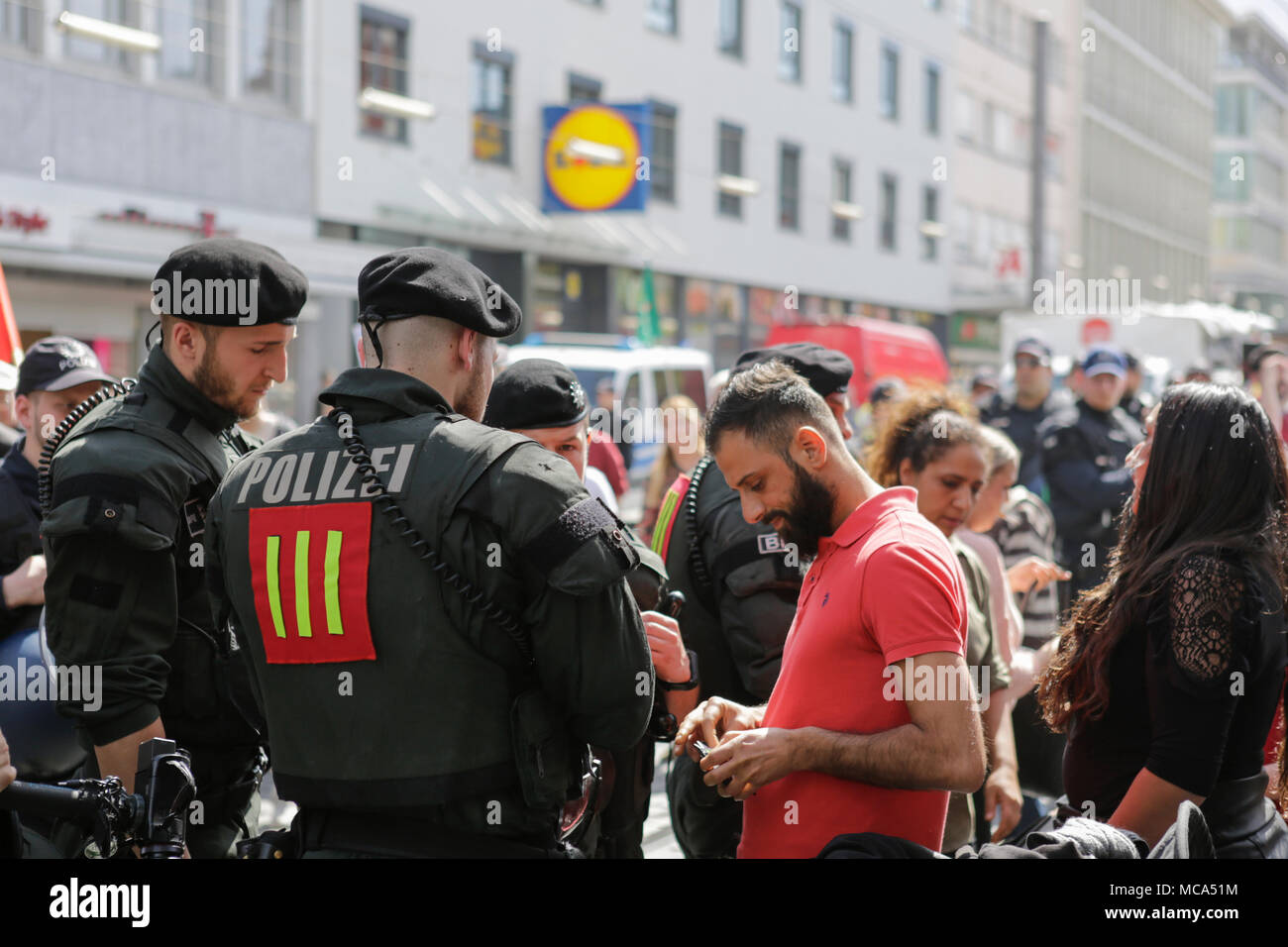 Mannheim, Germania. Il 14 aprile 2018. Un passante da ha la sua identità controllati da funzionari di polizia. Il popolo curdo e i tifosi tedeschi hanno marciato attraverso Mannheim per protestare contro la continua occupazione della città siriana di Afrin, che era controllata dalla popolare curda Unità di Protezione (YPG) prima che hai conquistato dall'esercito turco. Essi inoltre hanno protestato contro la partecipazione tedesca attraverso le esportazioni di armi alla Turchia. Credito: Michael Debets/Alamy Live News Foto Stock