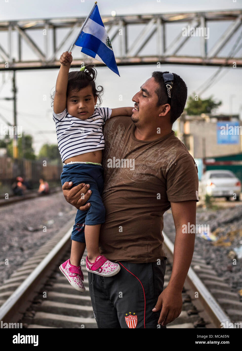 13 aprile 2018, Messico Città del Messico: un uomo porta un bambino sul suo braccio che regge la bandiera nazionale di El Salvador in mano come l'attesa per proseguire il trasporto attraverso il Messico. Ogni anno numerosi migranti dall Honduras, Guatemala e El Salvador fissati per gli Stati Uniti per chiedere asilo, viaggiando in grandi gruppi per proteggersi dalle piste e cartelli lungo la strada. Foto: Gerardo Vieyra/dpa Foto Stock