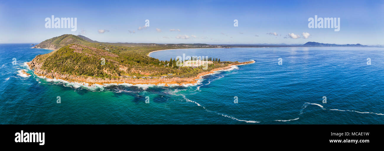 Emerald seascape panorama di Arakoon parco nazionale di costa con punto di riferimento di Trial Bay Gaol rovine su una soleggiata giornata splendente elevati vista aerea. Foto Stock
