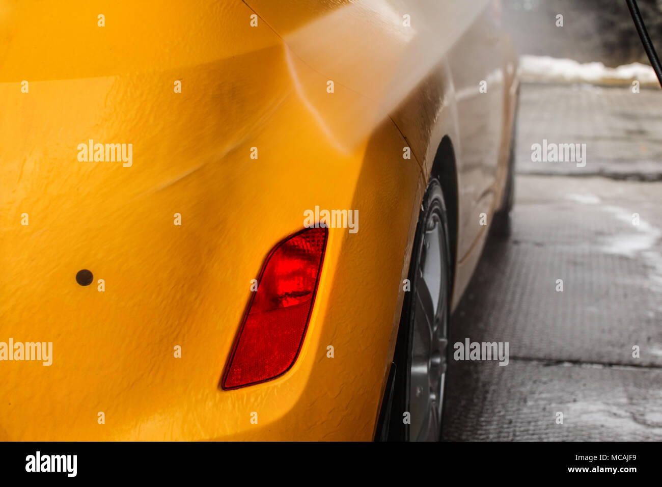 Dettagli sul giallo scuro vettura nuovamente di essere lavati con getto di acqua in flusso di autolavaggio. Foto Stock